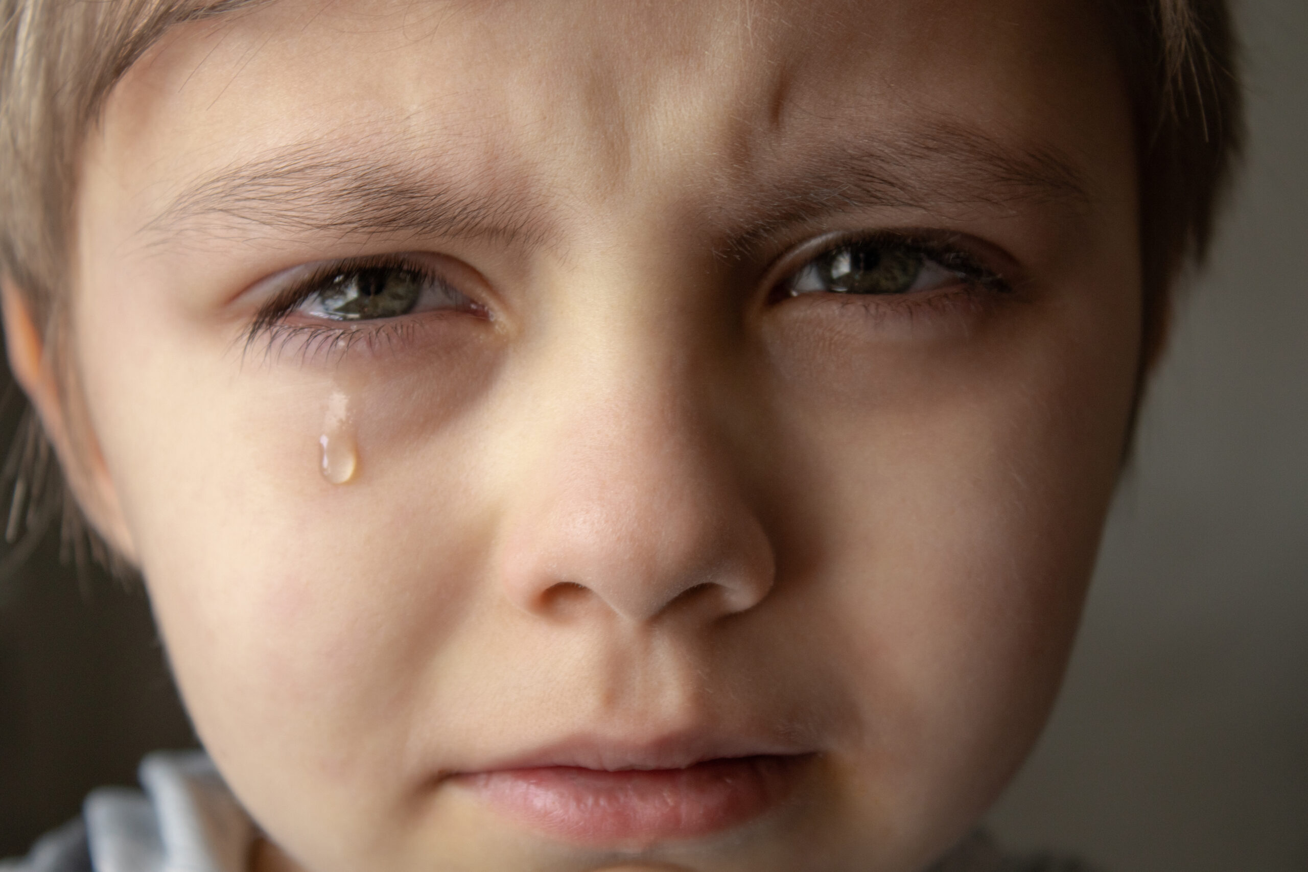 Tears in the eyes of a child. A tear on the boy's cheek.