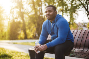 Man resting on bench after exercise and drinking water .