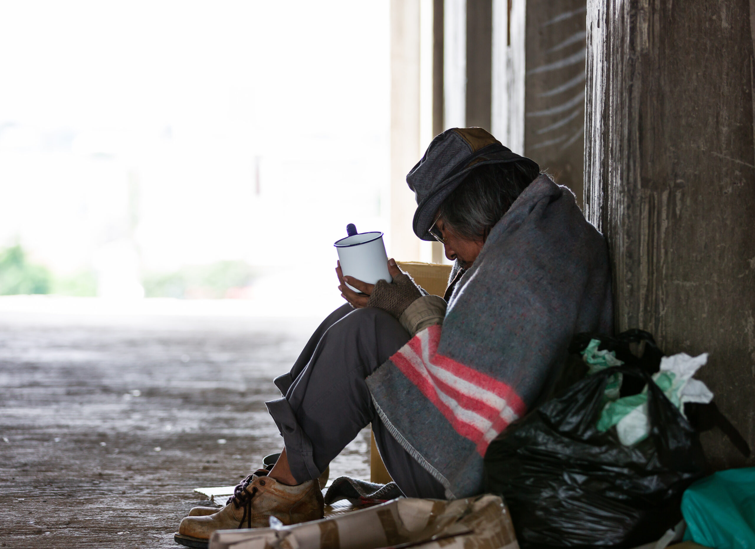 Homeless man sitting need money or food in an abandoned building or on street