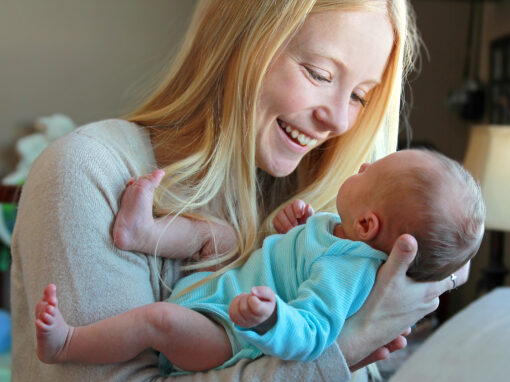 Young Mother Smiling at Newborn Baby in Home Nursery