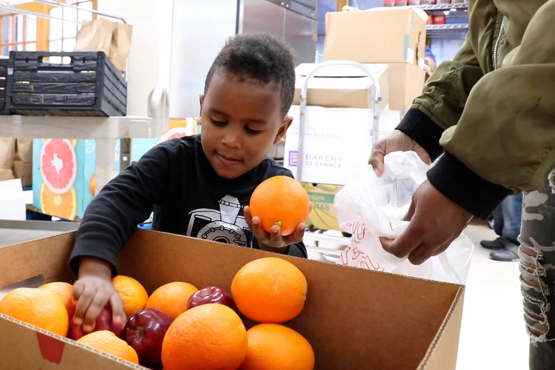 Child selecting produce at Catholic Charities' food pantry.